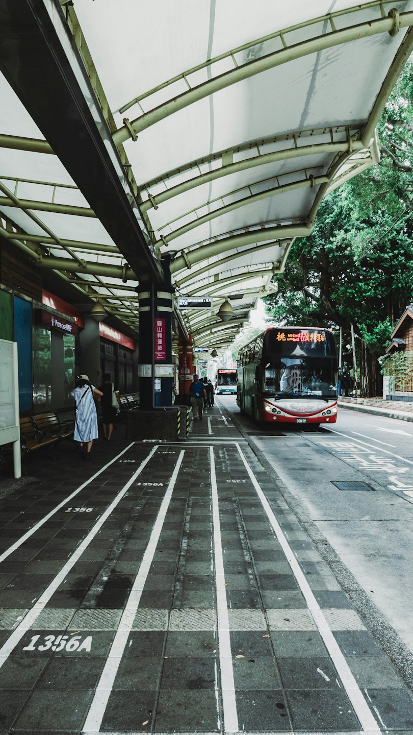 En rød buss nærmer seg et moderne, urbant stasjons-tak.